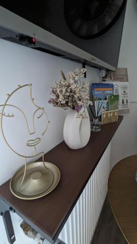 a desk with a vase of flowers and a lamp at Perle Urbaine : Jardin Spacieux! in Saint-Gratien