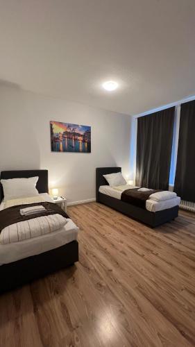 two beds in a room with wooden floors at Zentrale 2-Zimmer-Monteurwohnung in Neumünster in Neumünster