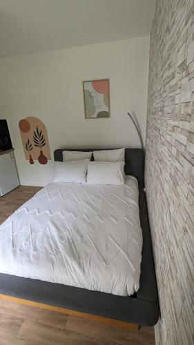 a bed in a bedroom with a brick wall at Perle Urbaine : Jardin Spacieux! in Saint-Gratien