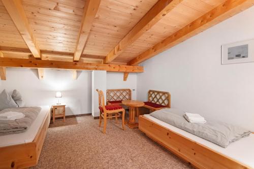 a bedroom with two beds and a table and chairs at Apartment am Reschensee in San Valentino alla Muta
