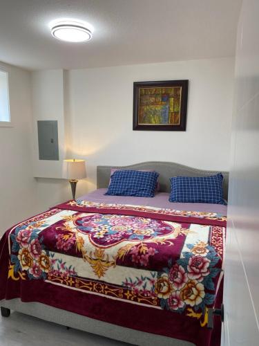 a bedroom with a bed with a colorful blanket and blue pillows at Cozy 2-Bedroom Suite in Aspen Ridge in Saskatoon