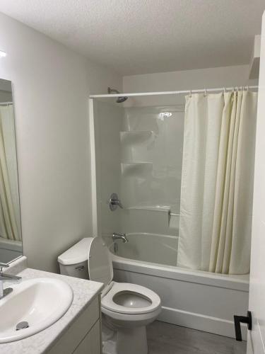 a white bathroom with a toilet and a sink at Cozy 2-Bedroom Suite in Aspen Ridge in Saskatoon
