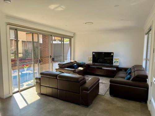 a living room with leather couches and a television at House in Burwood 2134 in Sydney