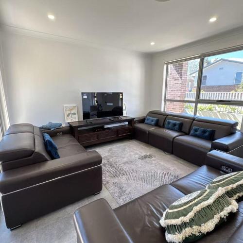 a living room with a couch and a flat screen tv at House in Burwood 2134 in Sydney