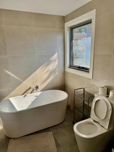 a bathroom with a tub and a toilet and a window at House in Burwood 2134 in Sydney