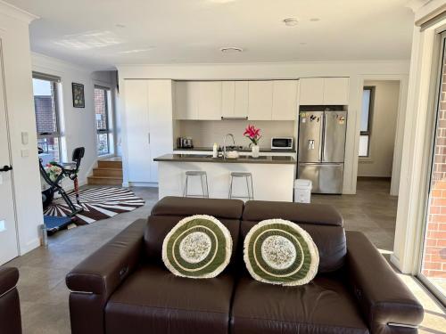 a living room with a brown couch and a kitchen at House in Burwood 2134 in Sydney