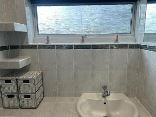 a bathroom with a sink and a window at Truehome Close to Stansted Airport in Harlow