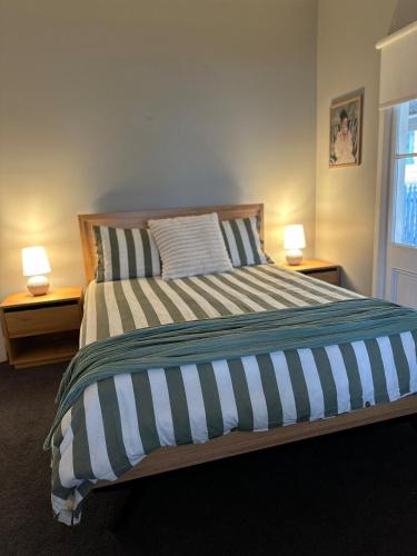 a bedroom with a bed with two lamps on two tables at Wattle Cottage in Cootamundra
