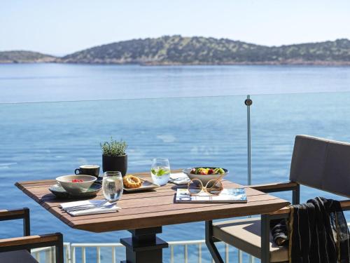 a table with food on it with a view of the water at NIKO Seaside Resort MGallery in Agios Nikolaos