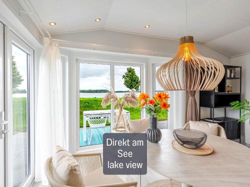 a dining room with a table and a large window at Strandperle Lathum Ferienhaus in Premium Lage am See für Urlaub und Workation mit Hundestrand in Lathum