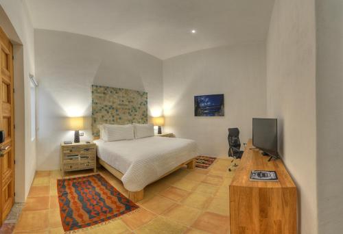 a bedroom with a bed and a desk with a television at Hotel Boutique Casareyna in Puebla