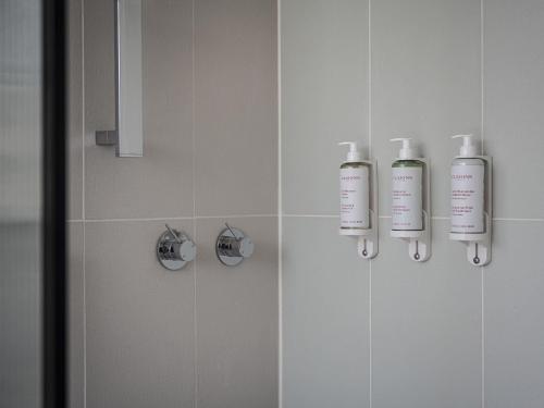 a bathroom with two shampoo bottles on the wall at Elkonin Tel Aviv - MGallery Hotel Collection in Tel Aviv