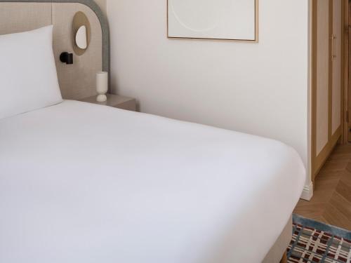 a bedroom with a white bed with a picture on the wall at Elkonin Tel Aviv - MGallery Hotel Collection in Tel Aviv