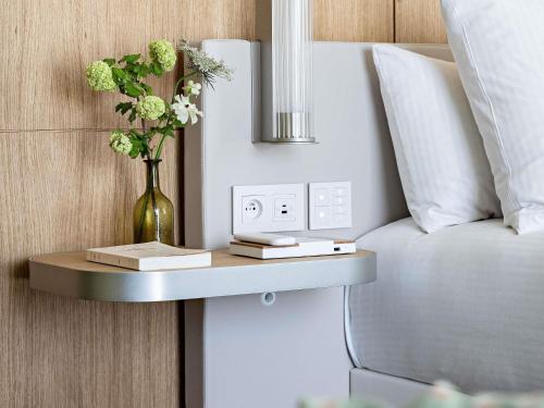 a vase of flowers on a shelf next to a bed at Domaine de la Reine Margot Paris-Issy - MGallery Collection in Issy-les-Moulineaux