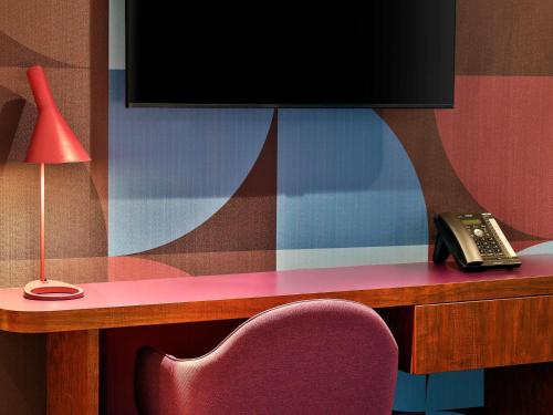 a desk with a tv and a phone and a chair at Queen Elizabeth 2 Hotel in Dubai