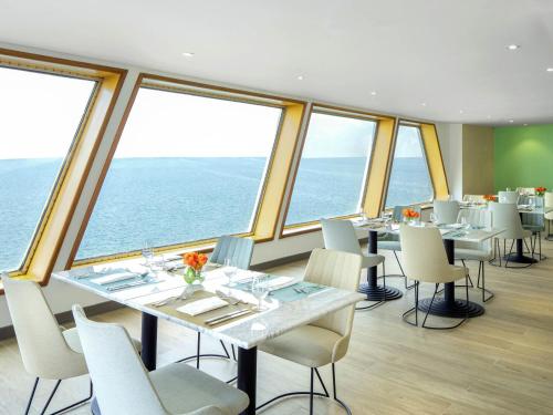 a restaurant with tables and chairs in a room with windows at Queen Elizabeth 2 Hotel in Dubai