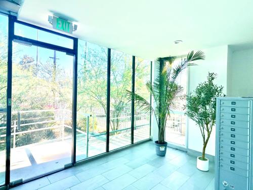 a room with large glass windows and plants in it at Modern New Studio Cozy&Prime Location in North Sherman Way