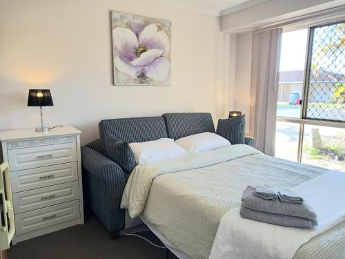 ein Schlafzimmer mit einem Bett, einer Kommode und einem Fenster in der Unterkunft 3mins walk to shopping centre city bus airport train station in Brisbane