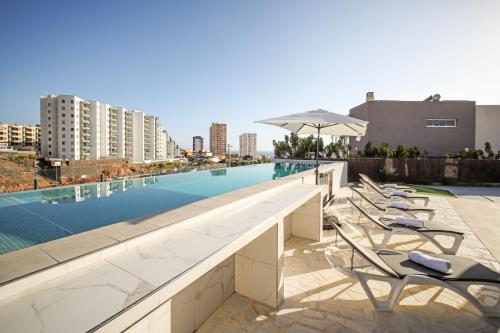a swimming pool with chairs and an umbrella on a building at Nirvana - Luxury Villa with heated pool in Playa Paraiso