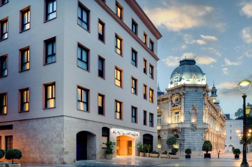 ein weißes Gebäude neben einem Gebäude mit einem Uhrenturm in der Unterkunft AC Hotel by Marriott Cartagena in Cartagena