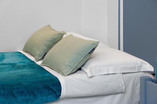 a white bed with four pillows on it at Oasi Apartament a 10 minuti dal Ospedale San Raffaele in Vimodrone