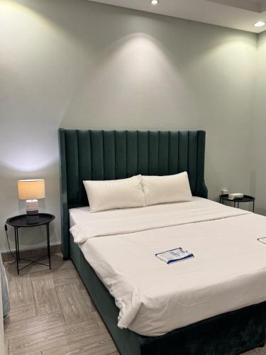 a bed with a green headboard in a room at In Apartments in Jeddah