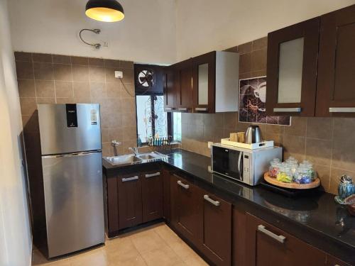 a kitchen with a stainless steel refrigerator and a microwave at Cocoa Bliss in Manesar
