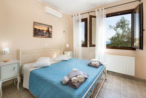 a bedroom with a blue bed with towels on it at Villa Elpida in (( Klonátika ))
