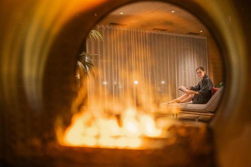 a man sitting on a couch in front of a mirror at Hotel Anewandter in Brunico