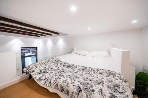 a white bedroom with a bed with a black and white comforter at Tonight Homestay South Shanxi Road Shanghai in Shanghai