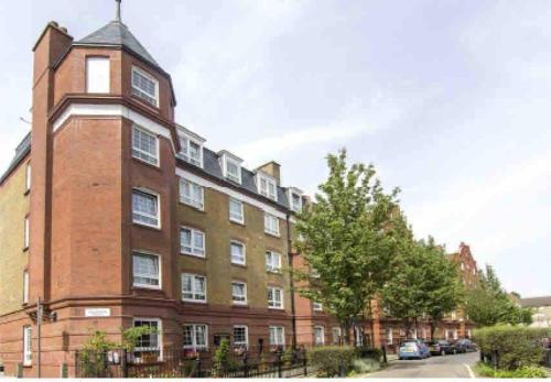 a large brick building with a clock tower on a street at Open plan stylish urban flat in London