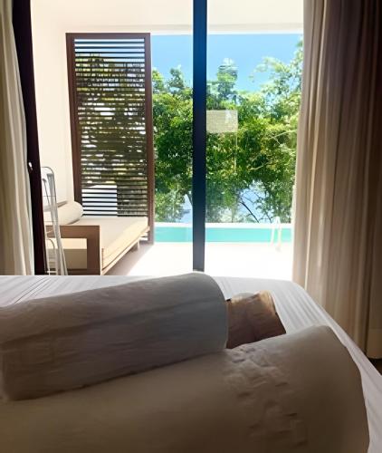 a bedroom with two beds and a large window at MAR DÁ LIBERDADE com Amerigo Vespucci in Morro de São Paulo