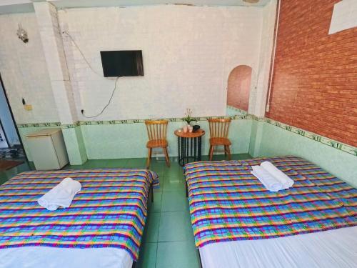 two beds in a room with a tv and two chairs at QUANG'S nhà nghỉ in Thôn Kim Long (1)