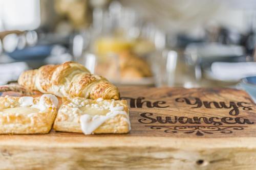 a table with croissants and pastries on a cutting board at Entire Venue Hire with 8 Bedroom Accommodation - Your Own Pub Experience in Swansea
