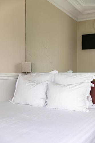 a white bed with white pillows in a bedroom at Hotel Claude Bernard Saint-Germain in Paris