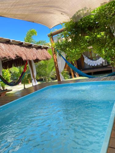 a swimming pool with a hammock in a resort at Bangalôs Flecheiras de Canaã in Flecheiras