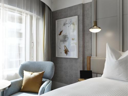 a bedroom with a bed and a blue chair at The Porter House Hotel Sydney - MGallery in Sydney