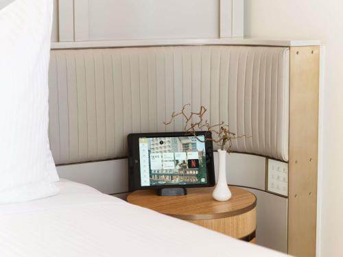 a computer sitting on a table next to a bed at The Porter House Hotel Sydney - MGallery in Sydney
