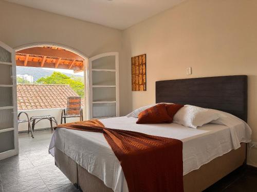 a bedroom with a bed and a table and a window at Suítes Aqui é Seu Lugar Itaguá in Ubatuba