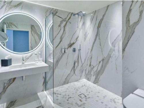 a bathroom with a shower and a sink and a mirror at La Licorne Hotel & Spa Troyes - MGallery Collection in Troyes