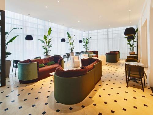 a lobby with couches and a table and chairs at La Licorne Hotel & Spa Troyes - MGallery Collection in Troyes