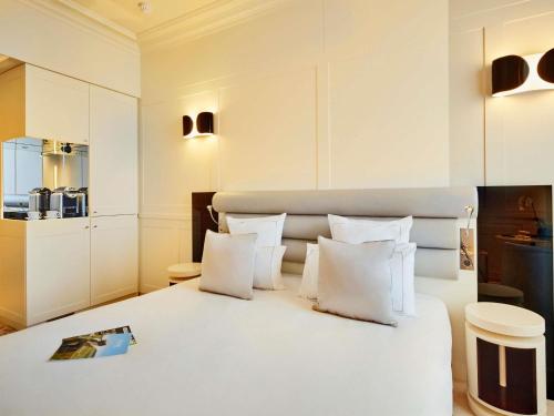a bedroom with a white bed with white pillows at La Licorne Hotel & Spa Troyes - MGallery Collection in Troyes