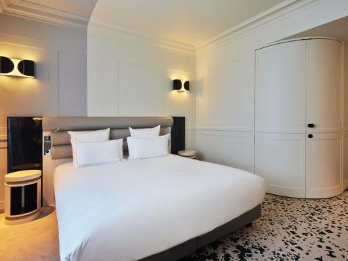 a bedroom with a large white bed with white pillows at La Licorne Hotel & Spa Troyes - MGallery Collection in Troyes