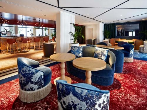 a lobby with blue chairs and tables and a bar at La Licorne Hotel & Spa Troyes - MGallery Collection in Troyes