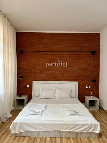 a bedroom with a white bed with a red brick wall at Vernisa hotel in Tbilisi City