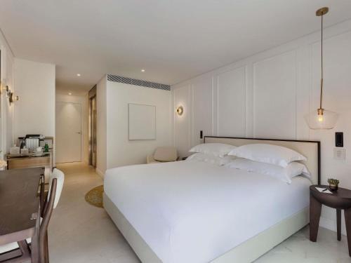 a white bedroom with a large white bed and a desk at Theatron Jerusalem Hotel & Spa - MGallery Collection in Jerusalem