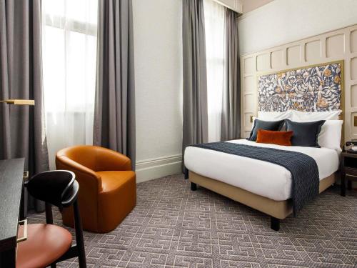 a hotel room with a bed and a chair at The Municipal Hotel Liverpool - MGallery in Liverpool