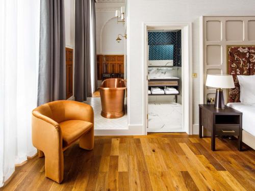 a bedroom with a chair and a tub in a room at The Municipal Hotel Liverpool - MGallery in Liverpool