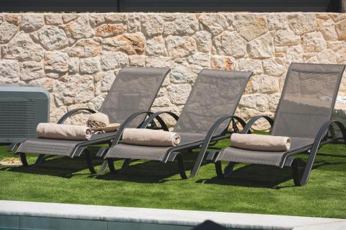 three lawn chairs sitting in front of a stone wall at LUV Group of 4 Villas in Kathiana in Kathiana