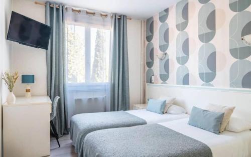 Una habitación de hotel con dos camas y un televisor. en Logis Hôtel Emeraude, en Confolens